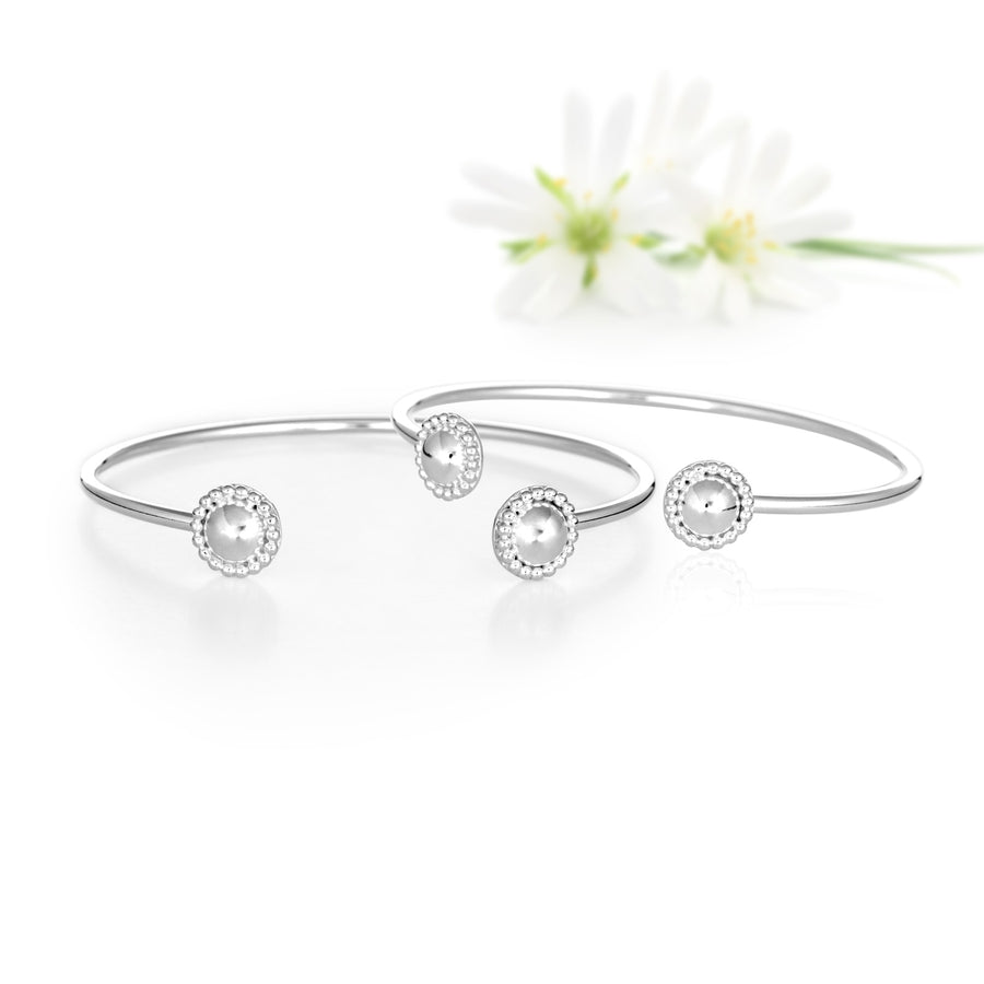 Two Bracelets Lying In Front Of White Flowers